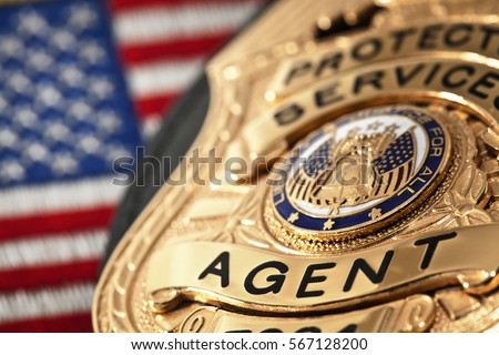 Fake prop badge with American flag in the background. Shallow depth of field with focus on the word agent.