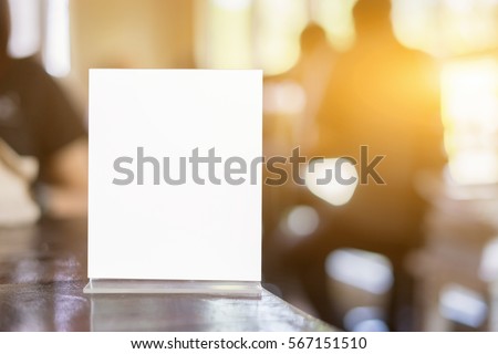 Mock up Menu frame on Table in Bar restaurant ,Stand for booklets with white sheets of paper acrylic tent card on cafeteria blurred background 