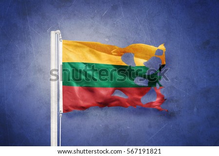 Torn flag of Lithuania flying against grunge background.