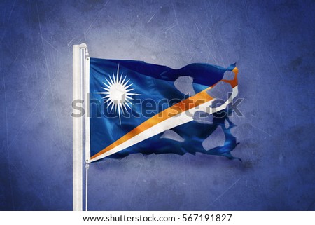 Torn flag of Marshall Islands flying against grunge background.