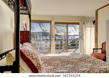 Sun filled bedroom interior boasts king size half canopy bed facing view of lake Washington through glass doors. Northwest, USA