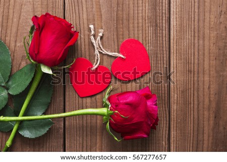 Label and red roses on wooden background