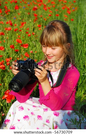 young girl taking photo of poppies on the meadow by professional camera