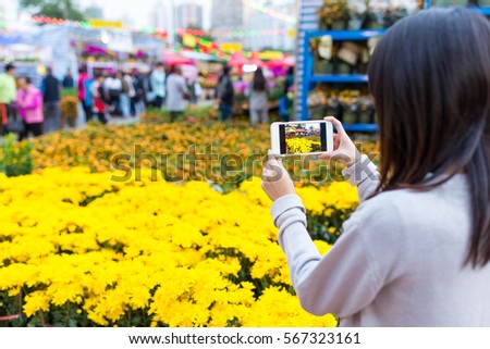 Woman taking photo with cellphone on Lunar new year flower market
