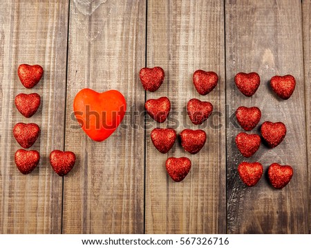 many red hearts on wooden background.