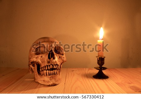 human skull with light candle in night time, still light photography.  