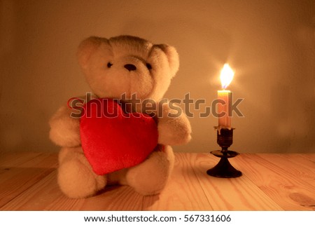 Teddy bear and  litter red heart with candle light background, sill life style