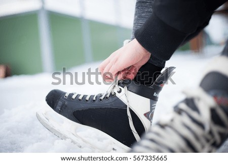 Young man hand commits laces on ice skates and prepare for ice skating