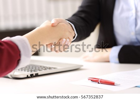 Close up of two businesswomen hands handshaking after closing a deal and signing contract in a desk with an office background