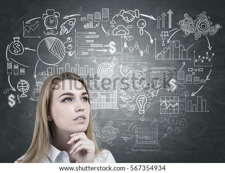Portrait of a pensive blond girl wearing a white blouse and standing near a blackboard with a start up drawing on it.