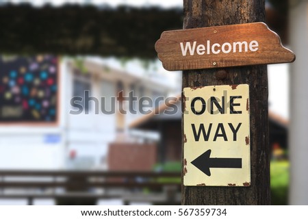 vintage wood welcome plate or signboard with one way guide post on old wooden pole in the restaurant or tourist attraction
