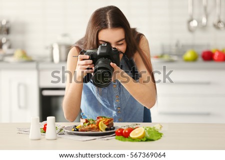 Young pretty woman photographing food in kitchen