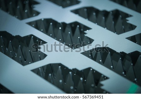Close up shut of a metal sheet with pieces cut out of it.