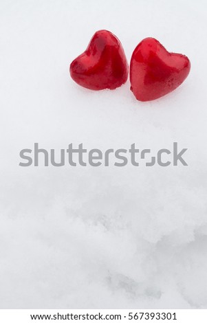  two  red hearts in the snow. Vertical photo, shallow depth of field