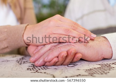 Close up picture of elderly man holding his granddaughter's hands