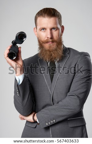 Bearded hipster business man in suit holding binoculars