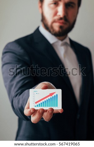 Man's hand showing business card with successful business graph. 