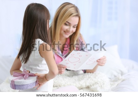Cute little girl hiding present for her mother behind back. Mother's day concept