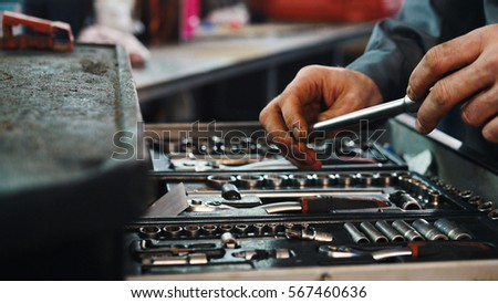 A set of tools for repair in car service - mechanic's hands, close up Royalty-Free Stock Photo #567460636