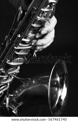 Man's hands with saxophone on burgundy background. Black and white photography