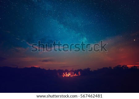 Camping fire under the amazing blue starry sky with a lot of shining stars and clouds. Travel recreational outdoor activity concept. Royalty-Free Stock Photo #567462481