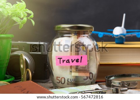 Jar with money for a travel, airplane, maps, passport, and other stuff for adventure on the blackboard background