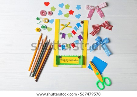 Handmade gift card and colorful crayons on white wooden background