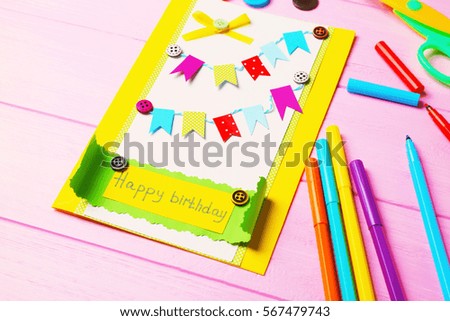 Handmade gift card and colorful felt tip pens on pink wooden background