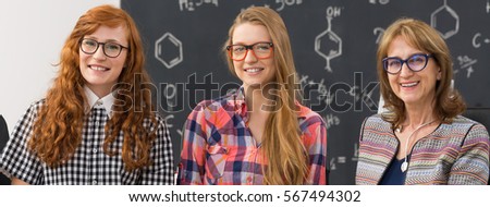 Portrait of smiling female professor and nerdy students in chemistry classroom