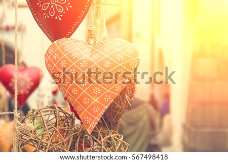 Orange and red heart decoration hanging on a rope and wicker rattan balls. Toned