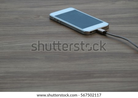 Mobile phone or Smartphone charging with power bank on wood background