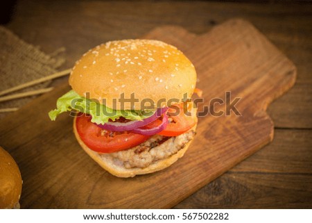 Cheese burger with grilled meat, cheese, tomato, on craft paper on wooden surface. Fast food template