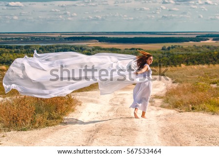 sunny day on the white trail running girl, wind waves a white cloth and long hair Royalty-Free Stock Photo #567533464