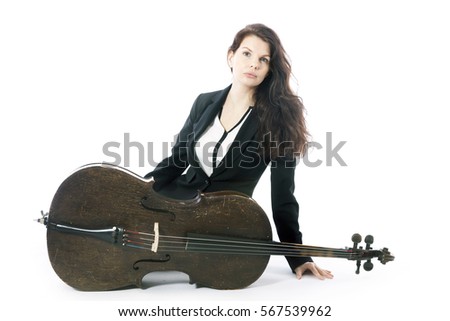 beautiful brunette woman sits on floor with old brown violoncello in studio against white background