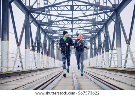 Photo of an athlete friends running on the train bridge in the morning.