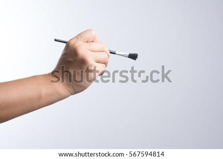Hand holding a brush on white background