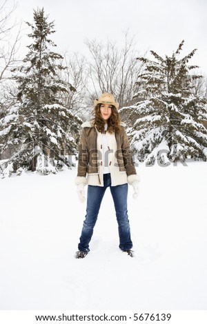 Caucasian young adult female standing in snow wearing straw cowboy hat.