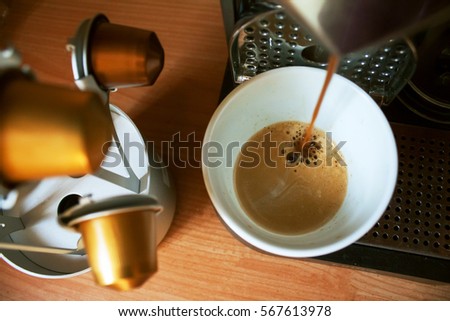 Morning cup of fragrant coffee from coffee machine on the wooden background with capsules holder Royalty-Free Stock Photo #567613978