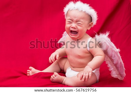 Sad baby cupid on red background