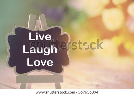 Live Laugh Love text written on blackboard with blur vintage background