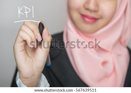 Business woman writing text : KPI over gray background