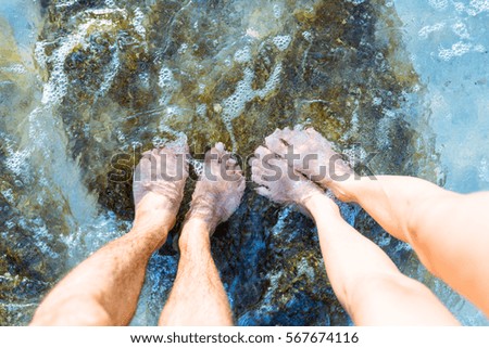 Man and woman, couples legs are standing in the clear water sea