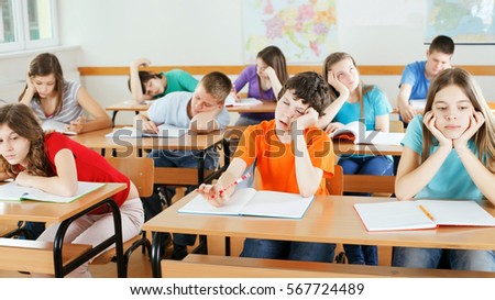 Group of bored pupils in a classroom, during lesson.