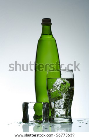 Cold purified water in the glass with bubbles and reflection on the wet background