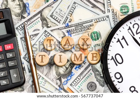 Words "TAX TIME" with clock and calculator on the money background. Business concept.