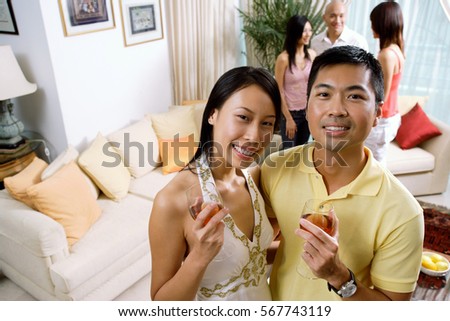 Couple with wine glasses, smiling at camera