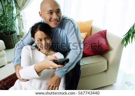 Couple in living room, woman holding remote control