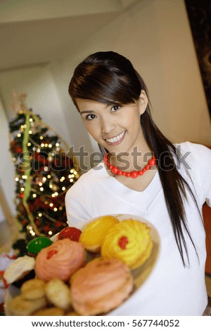 Woman holding plate of cookies, smiling at camera
