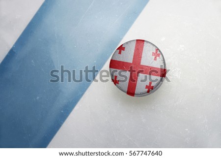 vintage old hockey puck with the national flag of georgia lies near the blue line