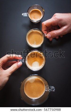 Cups of coffee in ascending order on the black background. man's and woman's hands holding a cups Royalty-Free Stock Photo #567750988